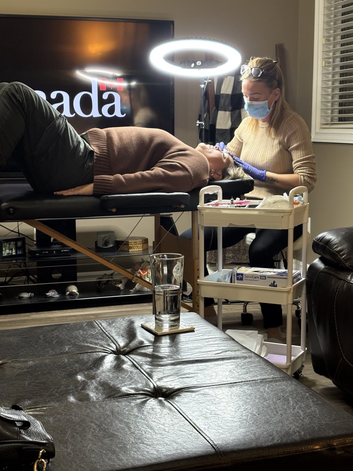 Amanda wearing a mask and gloves while working on a client's brows in a home treatment setup